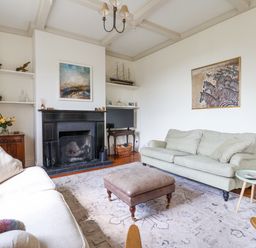 A living room with two sofas a fireplace a coffee table and shelves with decorations at Charmouth Lodge in Charmouth