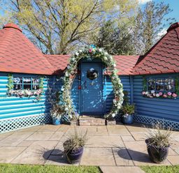 A blue cottage with a decorated door and roof at Applejacks Orchard in Holywell