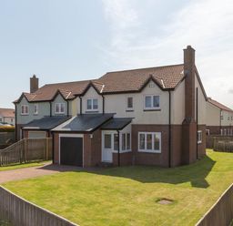 A semi detached house with a garage and fenced garden in a residential area at Driftwood Sands in Beadnell