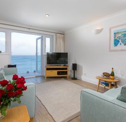 A living room with sofas a television and a view of the sea at Wavetop in Carbis Bay