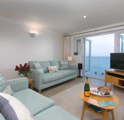 A living room with sofas a coffee table and a television with a view of the sea at Wavetop in Carbis Bay