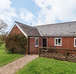 A brick house with a tiled roof a gravel path and green lawn at The Old Dairy in Whitchurch Canonicorum near Charmouth