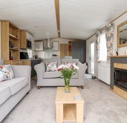 A living room with two sofas a coffee table with flowers and a fireplace at Silverdale View in East Heslerton near Sherburn