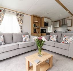 A living room with two gray sofas and a wooden coffee table with flowers at Silverdale View in East Heslerton near Sherburn