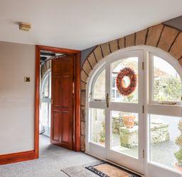 An entryway with a wooden door mirror and glass doors with a wreath at High Shaftoe in Ponteland