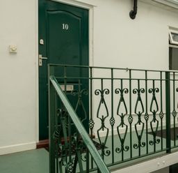 A green door with the number 10 and a decorative green metal railing on a balcony at The Gables Penthouse in Bournemouth