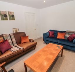 A living room with two sofas a wooden coffee table and abstract paintings on the wall at Tyne View Cottage in Bellingham