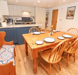 A kitchen and dining area with a wooden table set with plates and wine at The Byre in Carrshield near Allendale