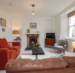 A living room with a sofa, armchair, coffee table, and fireplace at 84 Fore Street