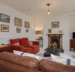 A living room with a sofa, fireplace and television at 84 Fore Street