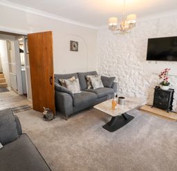 A living room with gray sofas a wall-mounted TV and a coffee table at Market Square Maisonette in Kirkby Lonsdale