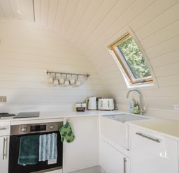 A kitchen with oven sink toaster kettle and hanging cups at Maple in Wootton Fitzpaine near Charmouth
