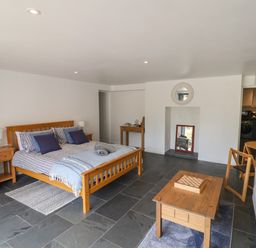 A bedroom with a wooden bed a coffee table with a chessboard and a small dining table at The Hideaway in Uplyme near Lyme Regis