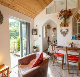 A small living area with a leather armchair a wooden table with two chairs and a view of a bedroom at Chateau Petit in Trefeglwys