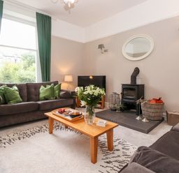 A living room with sofas a coffee table and a wood stove at Church View in Grange-Over-Sands