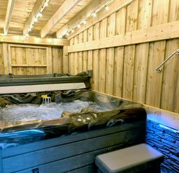 An indoor hot tub with bubbling water under string lights in a wooden room at Cranford House in Keswick