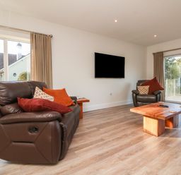 A living room with leather sofas wooden coffee table and wall-mounted television at Linden View in Combe Martin