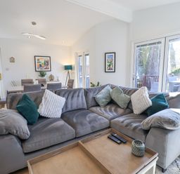 A living room with a gray sofa and cushions next to a dining table and chairs at Tranquil Waters Lakeside 16 White Cross Bay near Windermere