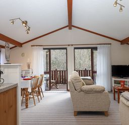 A living room with dining table chairs sofa television and kitchen counter at Teign River Retreat in Drewsteignton near Moretonhampstead