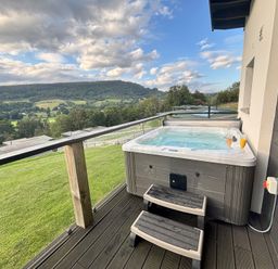 An outdoor area with a hot tub and drinks overlooking a mountain view at Osprey View Lodge & Hot Tub in Aberfeldy