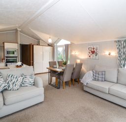 An open living space with two sofas, a dining table with chairs, and a kitchen area at No.7 Skiddaw View Moota near Aspatria