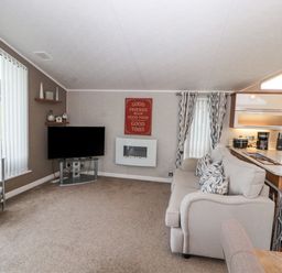 A living room with a sofa cushions television and shelves at No.7 Skiddaw View in Moota near Aspatria