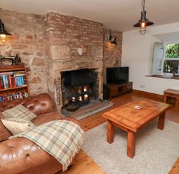 A living room with a fireplace and a sofa at Bruno's Bothy in Middleton near Belford
