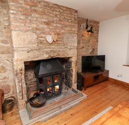 A living room with a fireplace and television at Bruno's Bothy Middleton near Belford