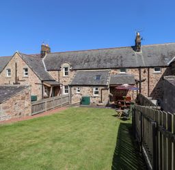 A garden area with cottages and outdoor furniture at Kits Cottage Middleton near Belford