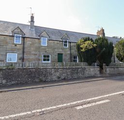 A stone cottage with green doors and windows near the road at Kits Cottage Middleton near Belford