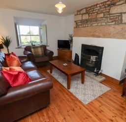 A living room with a fireplace and sofa at Kits Cottage Middleton near Belford