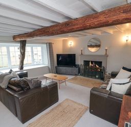 A living room with two leather sofas a wooden coffee table a fireplace a TV and exposed wooden beams at York House in Thornton Dale