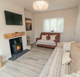 A living room with a fireplace a mounted television two sofas and a window at Ocean Spray in Scarborough