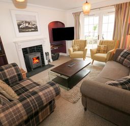 A living room with plaid sofas yellow armchairs a fireplace and a coffee table at The Old Boathouse in Trefin near St Davids