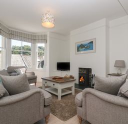 A living room with grey sofas a coffee table a fireplace and a television at 21 Passage Street formerly Panacea in Fowey