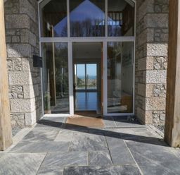 Stone entrance with glass door and wooden posts at Lower Mellan Barn in Coverack