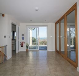 An entrance hall with tiled floor sliding glass doors and wooden framed mirrored closet doors at Lower Mellan Barn in Coverack