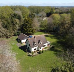 A detached house with a garage and a car on a grassy plot surrounded by trees at Rivendell in Weybread near Harleston