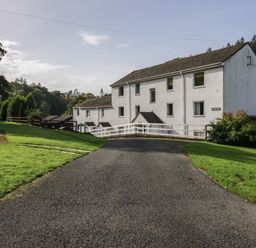A driveway leading to a white multi-story building surrounded by grass and trees at Apartment 2 in Keswick
