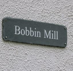 A wall with a rectangular sign reading Bobbin Mill