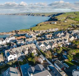 A coastal village with houses near the sea and green fields at Tre Lowen in Port Isaac