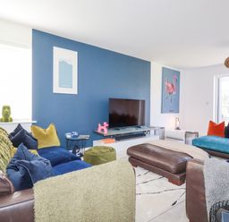 A living room with sofas and a television on a blue accent wall at Cobalt in St Eval near Mawgan Porth