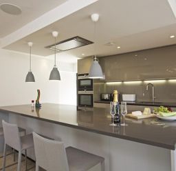 A modern kitchen with a large island and three pendant lights above at The Milking Shed in Bantham