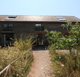 A building with windows and a door in a garden at The Milking Shed in Bantham