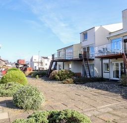 Exterior view of buildings with balconies stairs and bushes along a sidewalk at Sea Breeze in Porthmadog