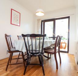A dining room with a table covered by a tablecloth and six wooden chairs near glass doors at Chi an Vre in Newlyn