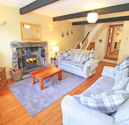 A living room with two sofas a wooden coffee table a fireplace and a television at Hafan Cottage in Beddgelert