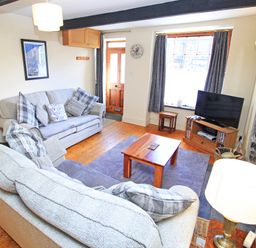 A living room with sofas a wooden coffee table a television and a fireplace at Hafan Cottage in Beddgelert