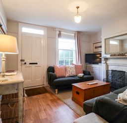 A living room with two sofas a wooden chest a fireplace and a lamp on a table at 3 Albion Cottages Walberswick