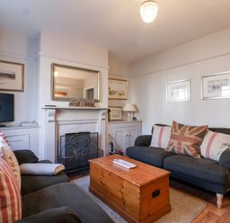 A living room with two sofas a wooden chest coffee table a fireplace and a television at 3 Albion Cottages Walberswick